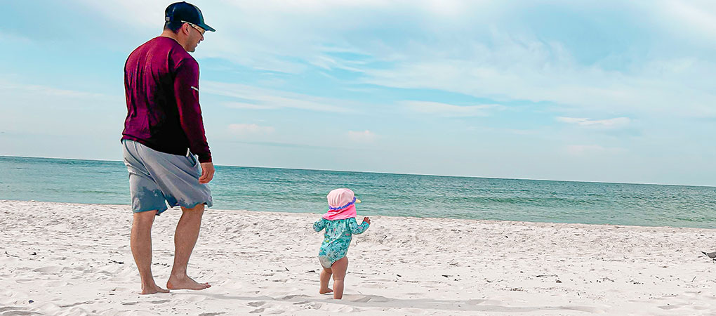 toddler and parent walking on beach